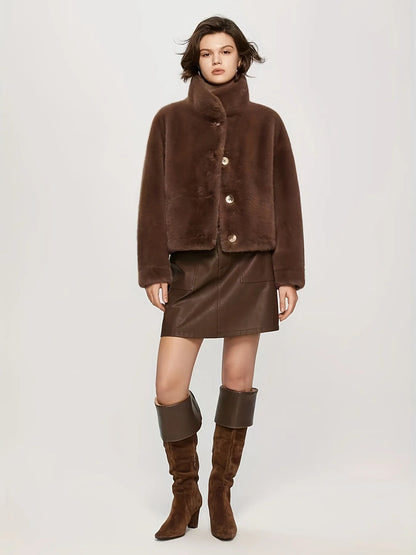 Woman wearing a brown outfit with a coat, skirt, and boots on a white background