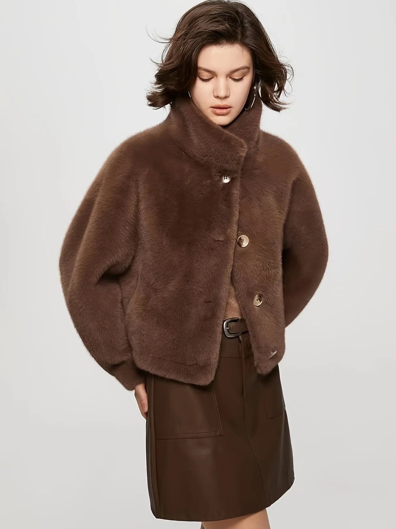 Woman wearing a brown fur coat and skirt on a white background
