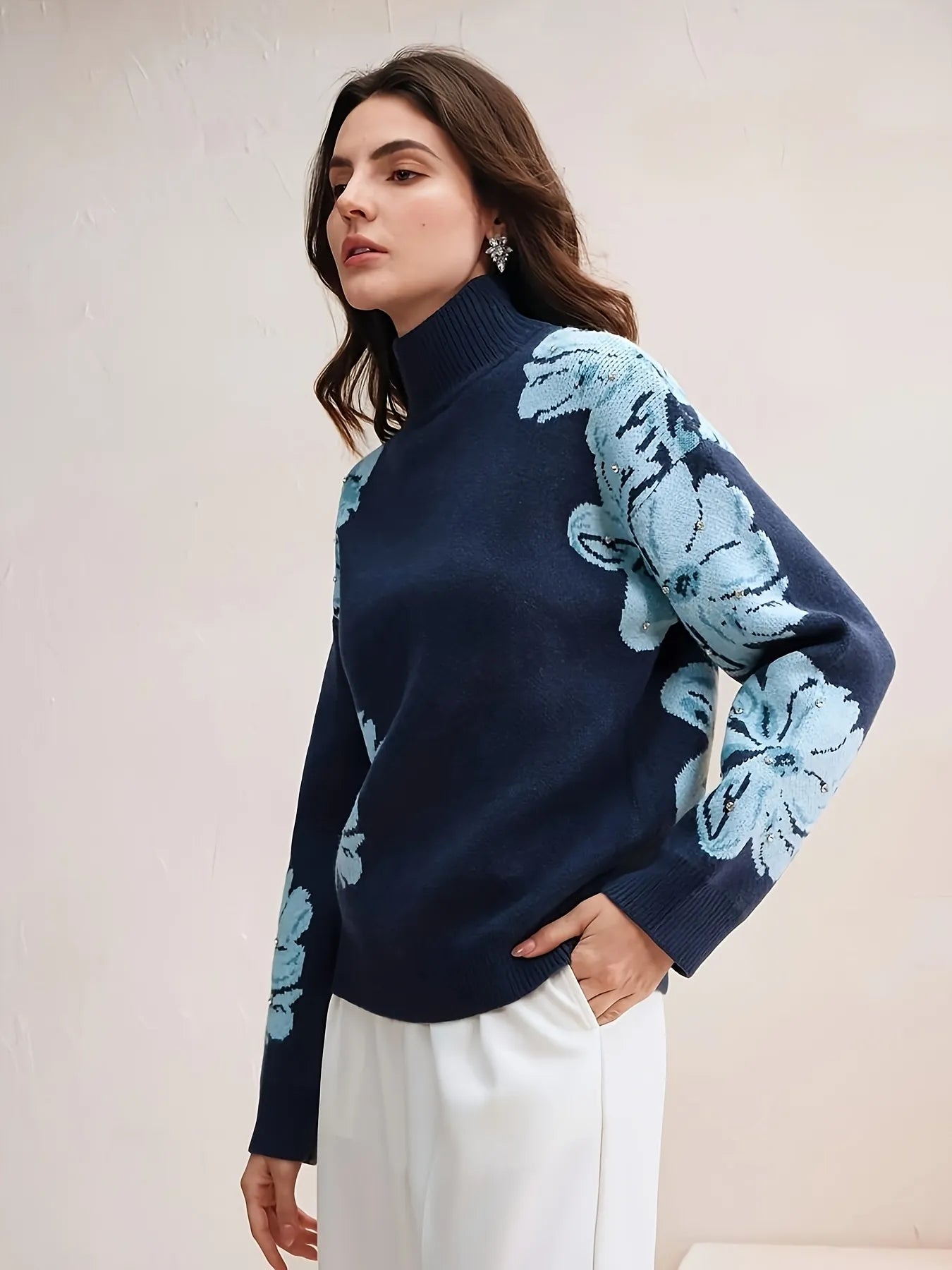 Woman wearing a navy sweater with light blue floral patterns against a plain background
