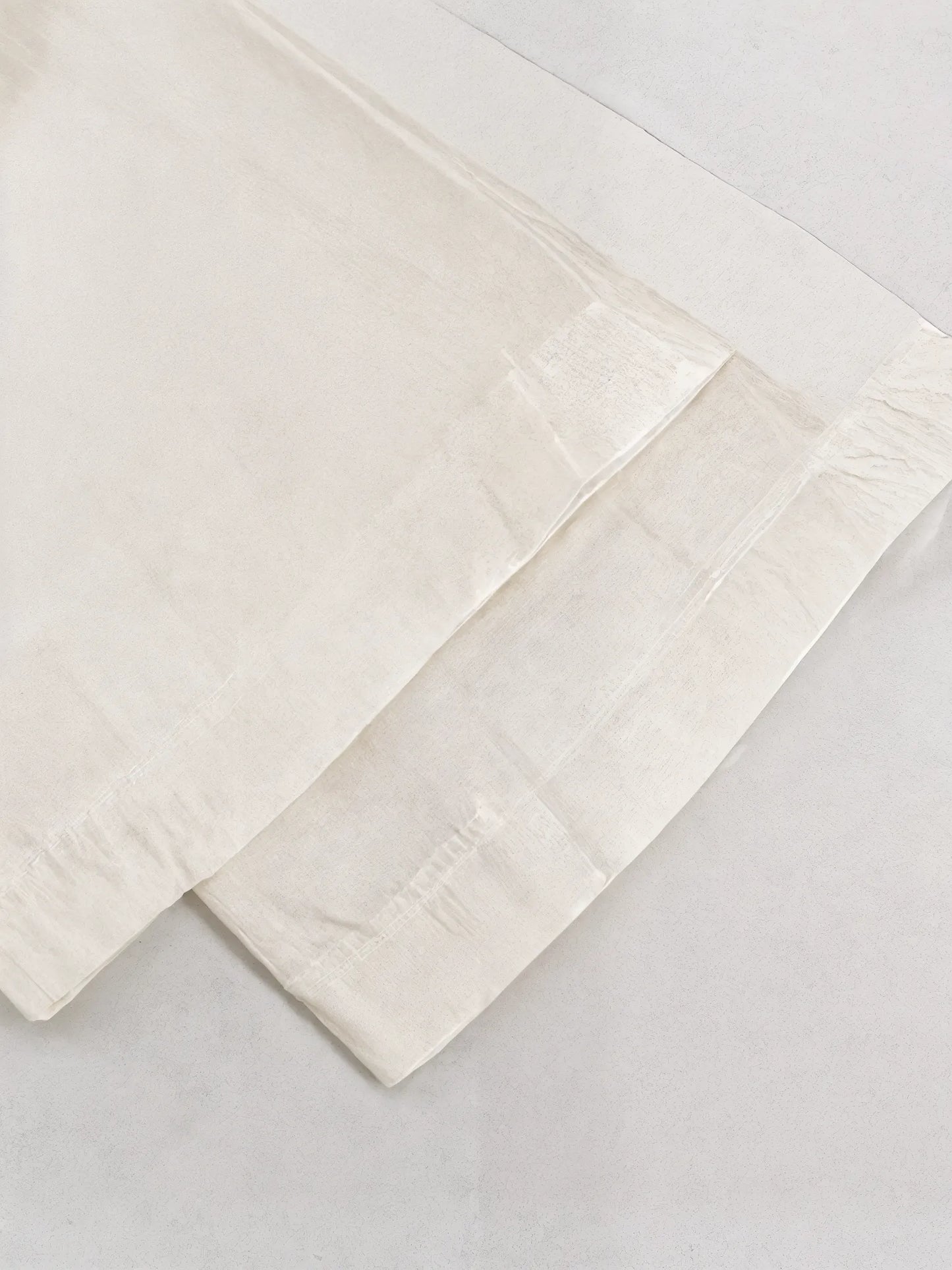 Two beige folded towels on a light gray background