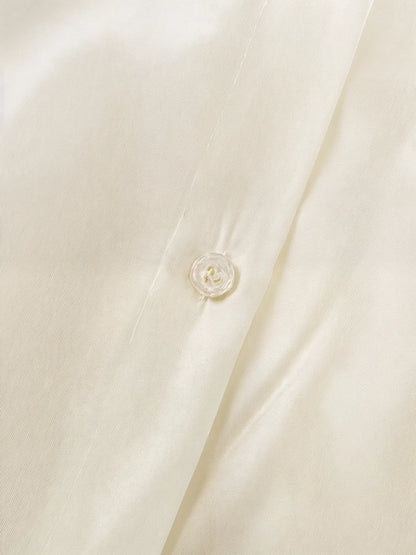 Close-up of a beige buttoned shirt with a button detail.