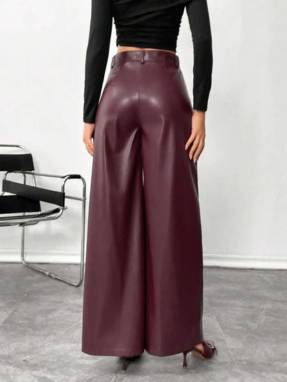 Person wearing burgundy leather pants with a black top against a white background