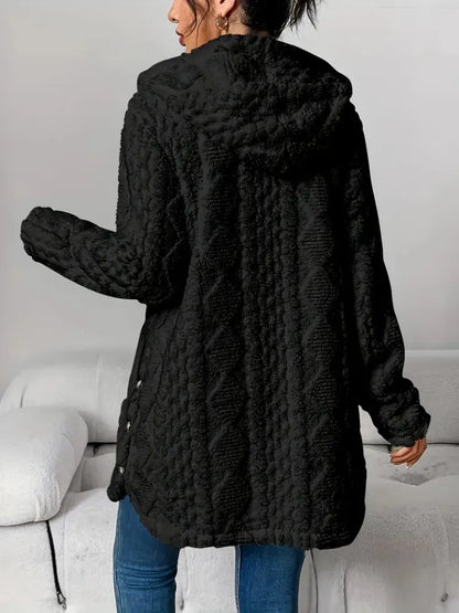 Person wearing a black textured coat in a minimal indoor setting