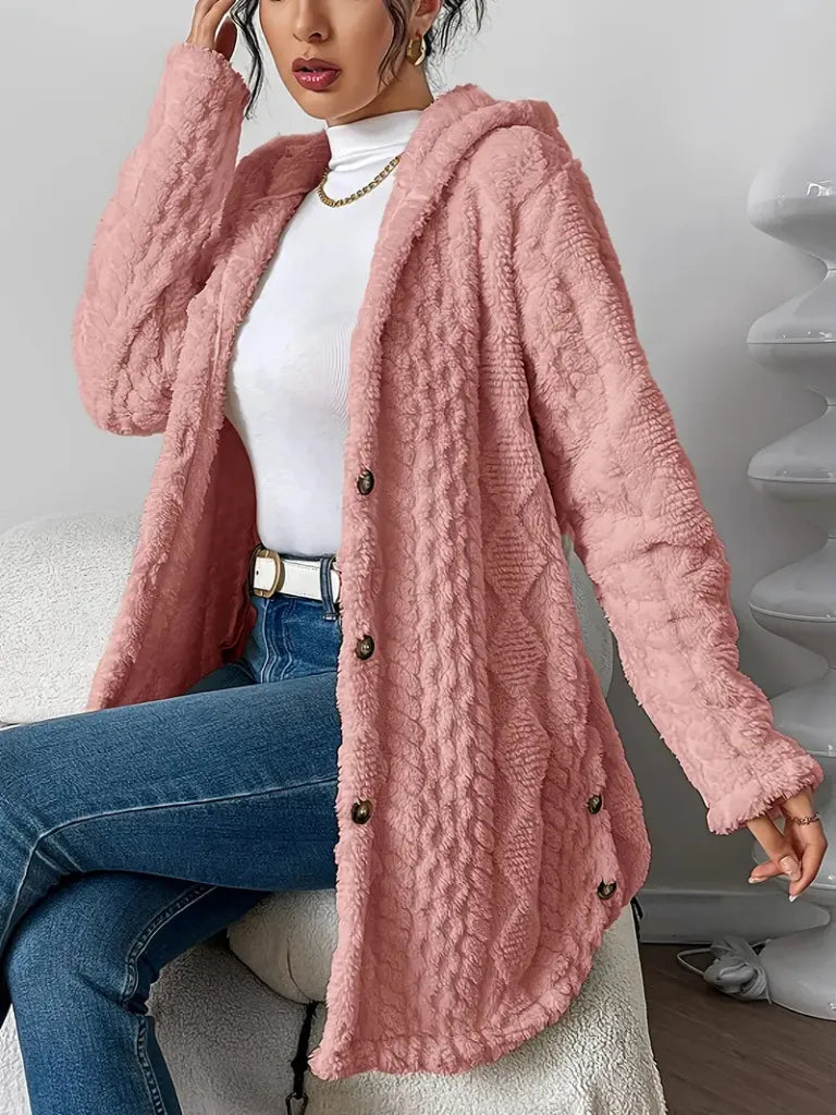 Person wearing a pink textured cardigan over a white top and blue jeans.
