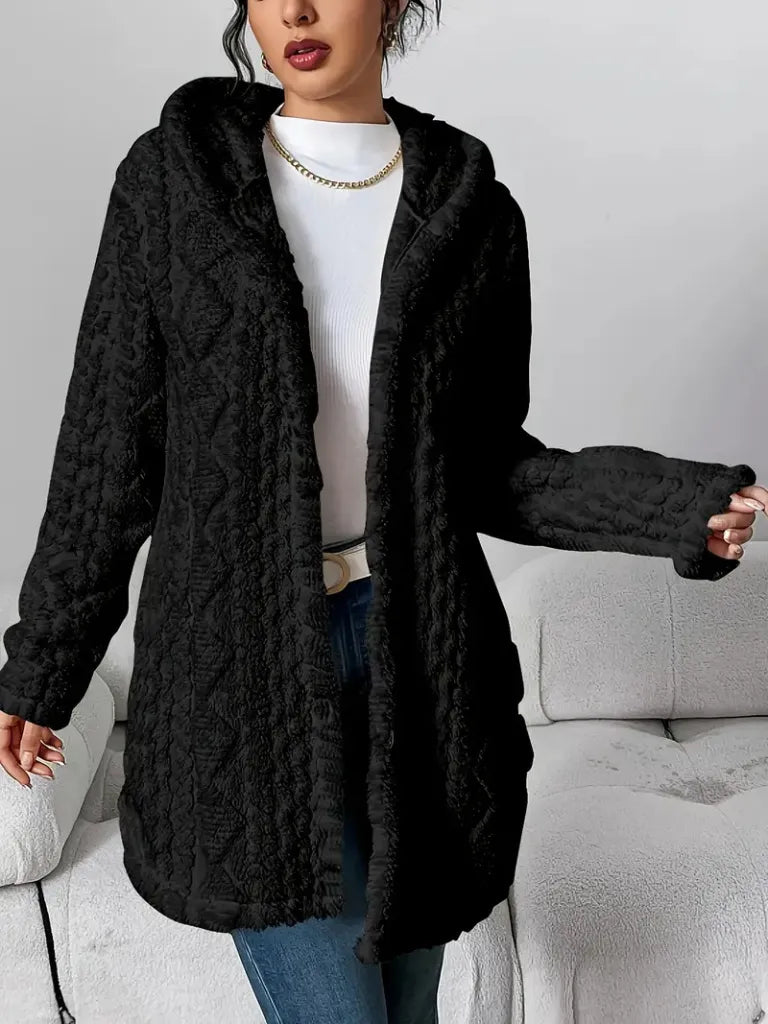Person wearing a black cable knit cardigan in a neutral setting