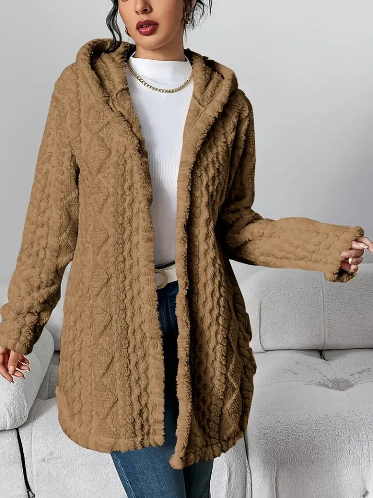 Person wearing a brown cable knit sweater with a hood in a neutral setting