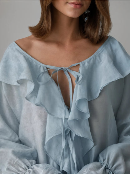 Light blue blouse with ruffled details and a tie front, worn by a person.