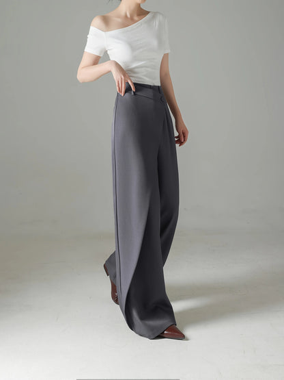 Person wearing a white off-shoulder top and gray wide-leg pants on a plain background