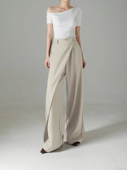 Person wearing a white off-shoulder top and beige wide-leg pants on a plain background