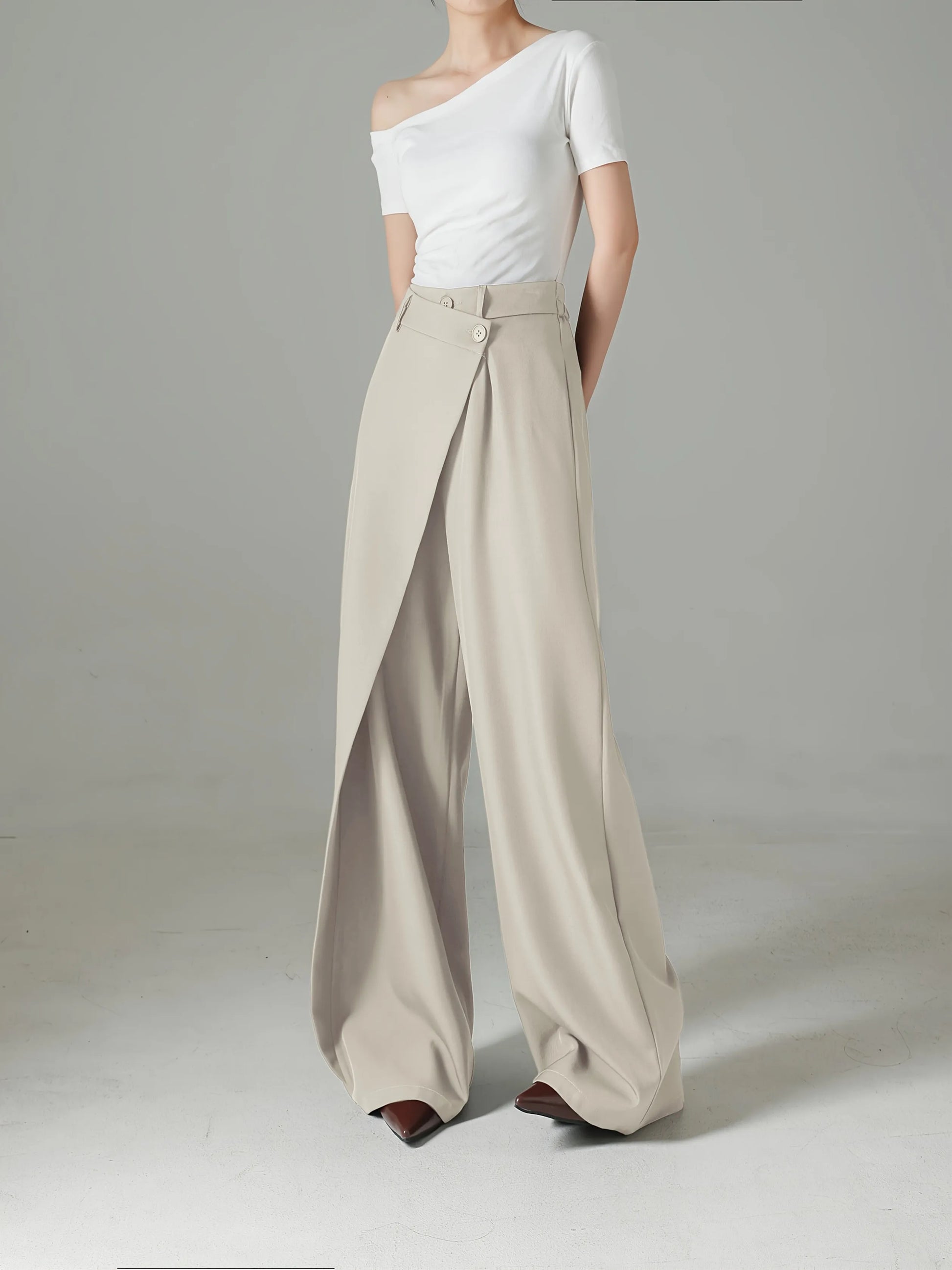 Person wearing a white top and beige wide-leg pants on a gray background