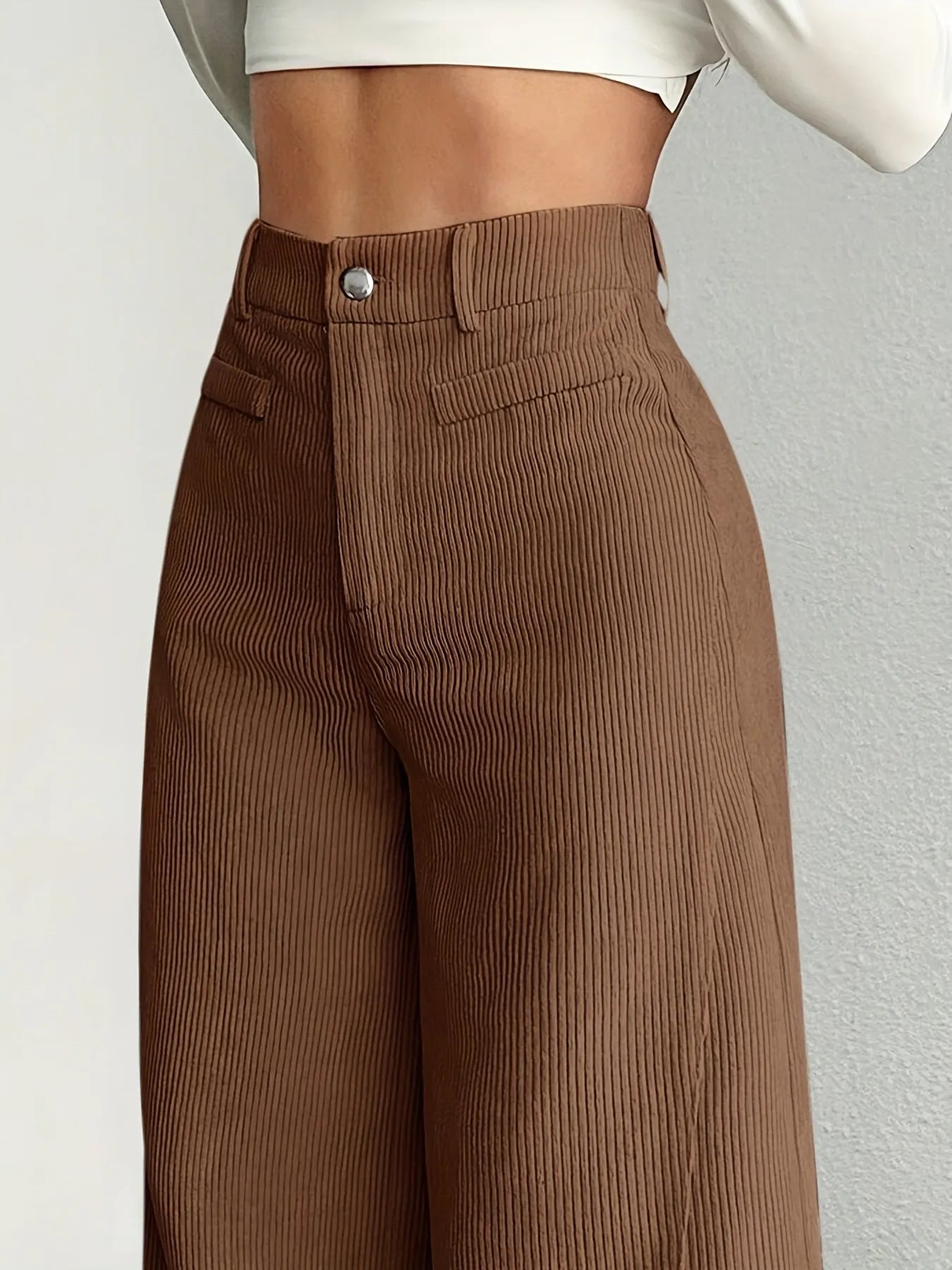 Brown ribbed pants worn by a person on a plain background