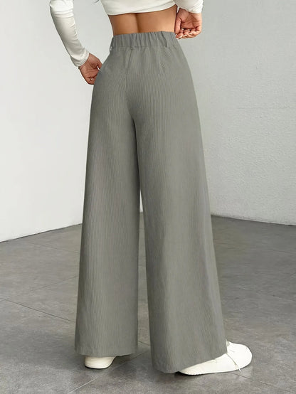 Person wearing gray wide-leg pants on a plain background