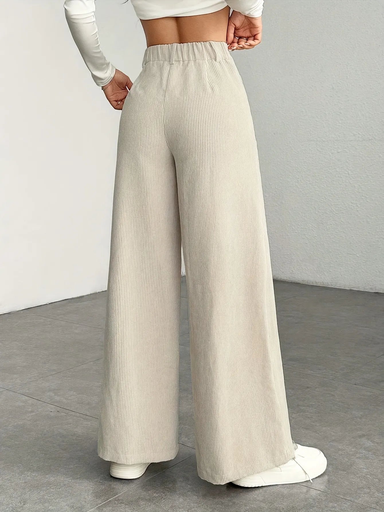 Person wearing beige wide-leg pants on a plain background