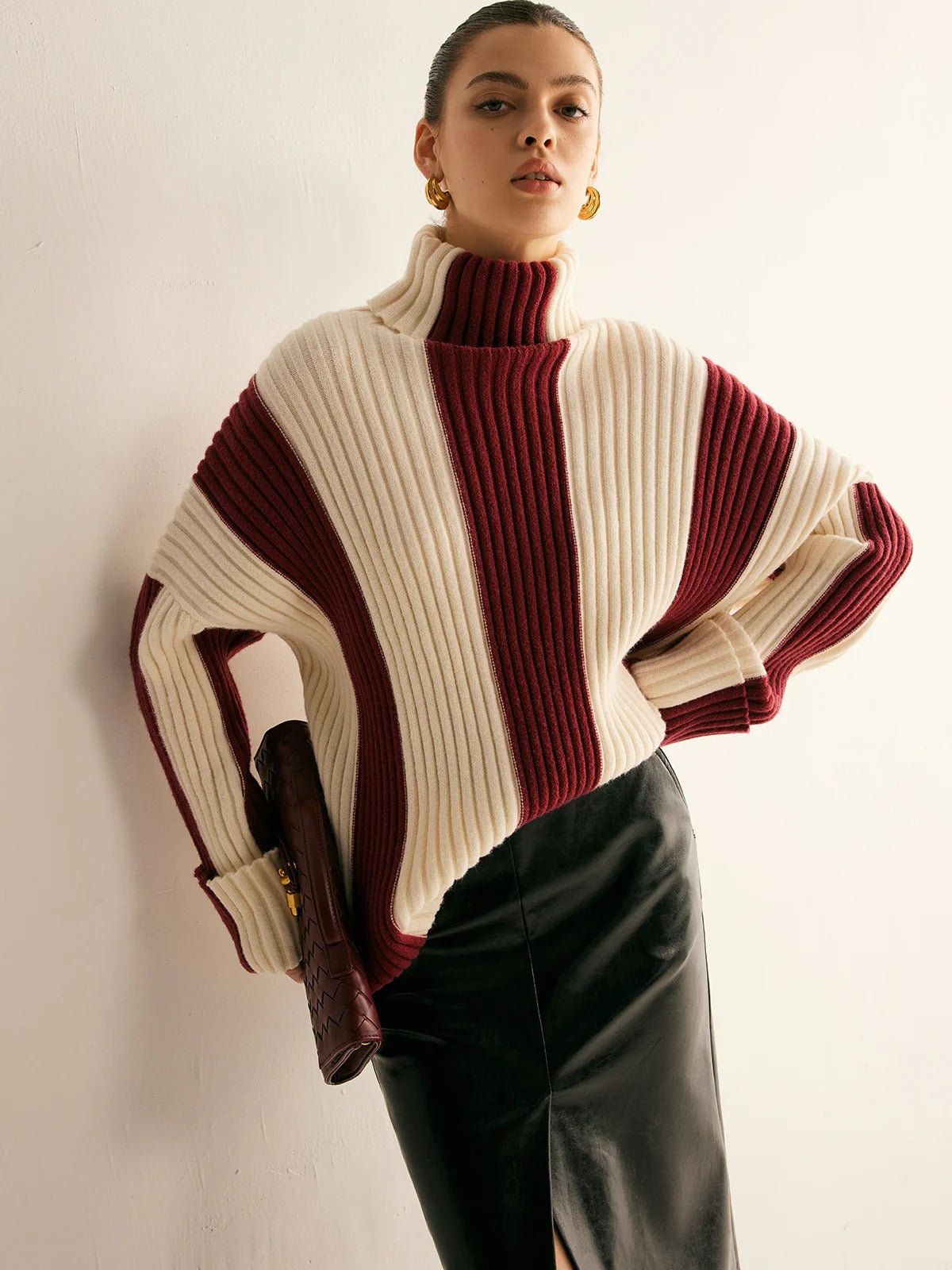 Person wearing a two-tone sweater with white and burgundy colors on a plain background
