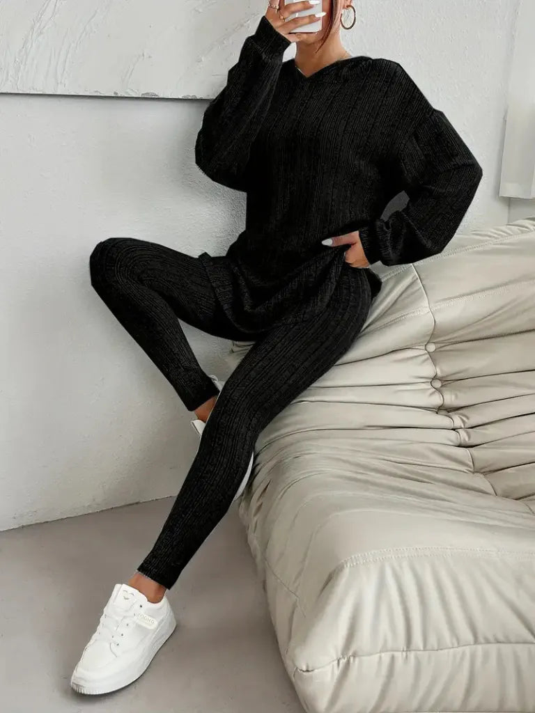Person wearing a black outfit with white sneakers sitting on a beige bean bag chair.
