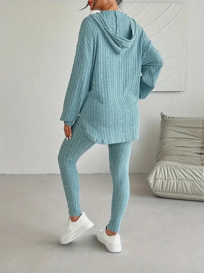 Person wearing a teal tracksuit in a minimalistic room.