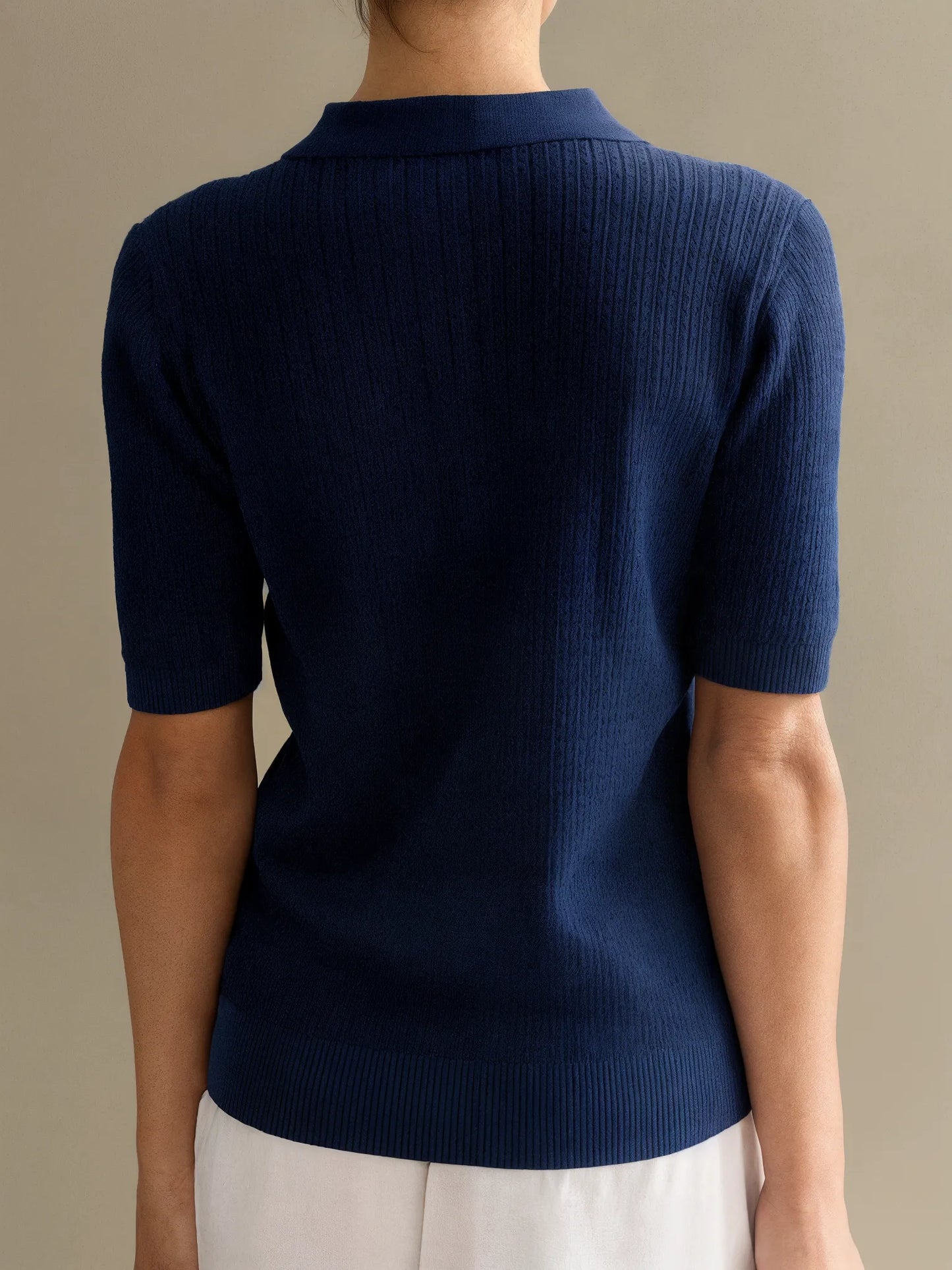 Navy blue short-sleeve sweater worn by a person on a beige background