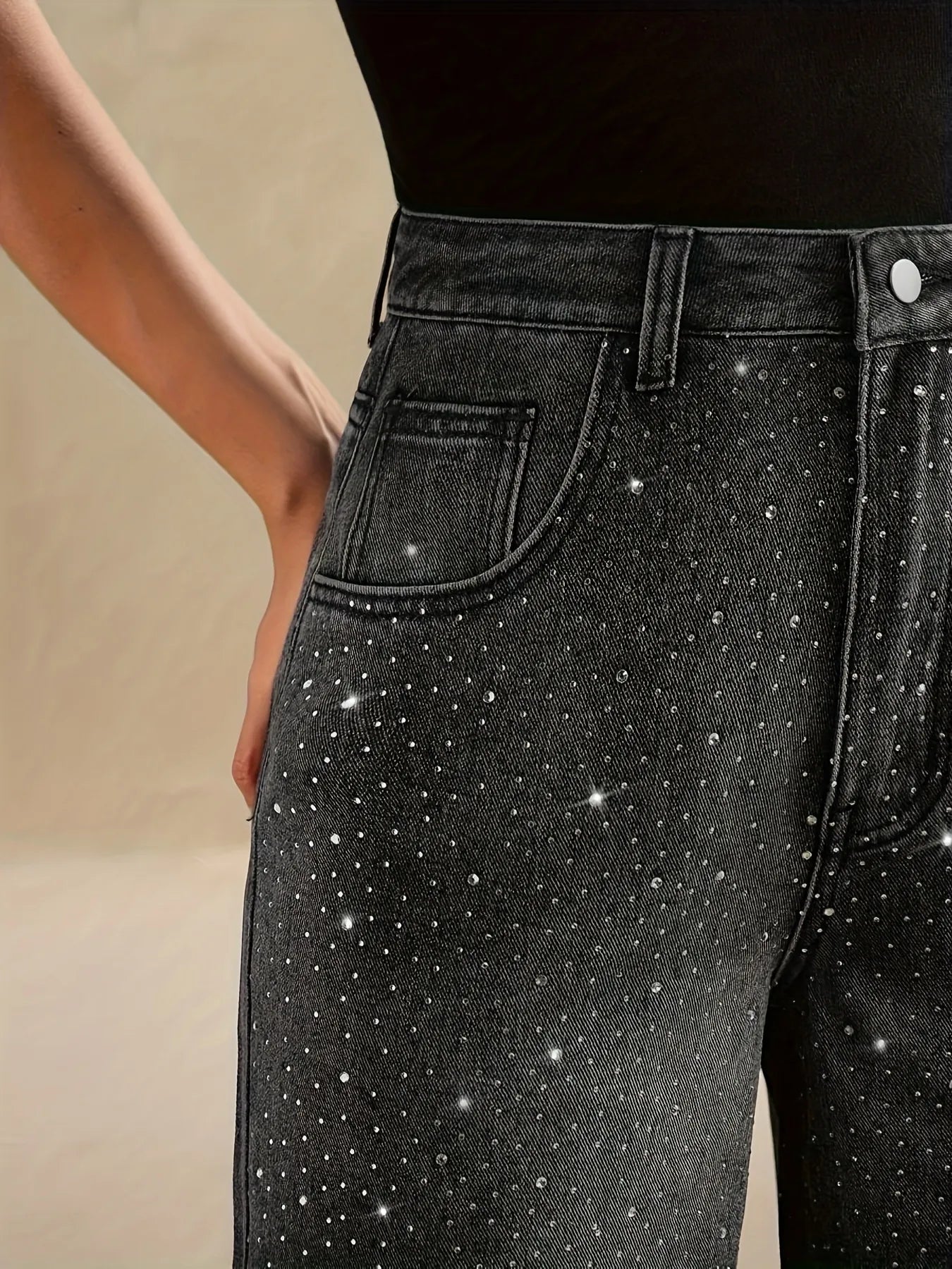 Black jeans with sparkling embellishments on a beige background