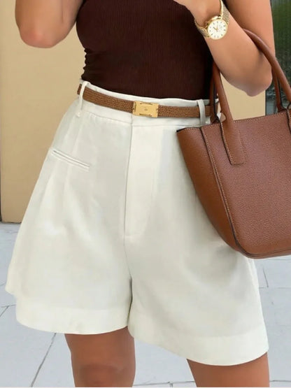 Person wearing white shorts, brown top, and holding a brown handbag.