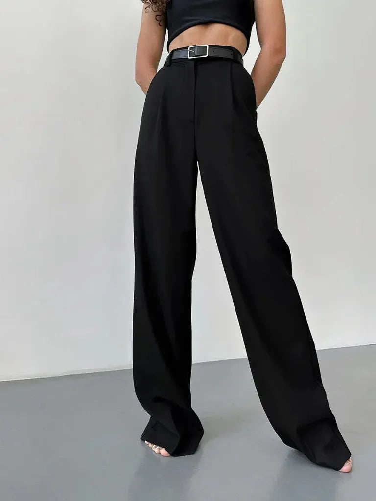 Person wearing black wide-leg pants and a black crop top on a plain background