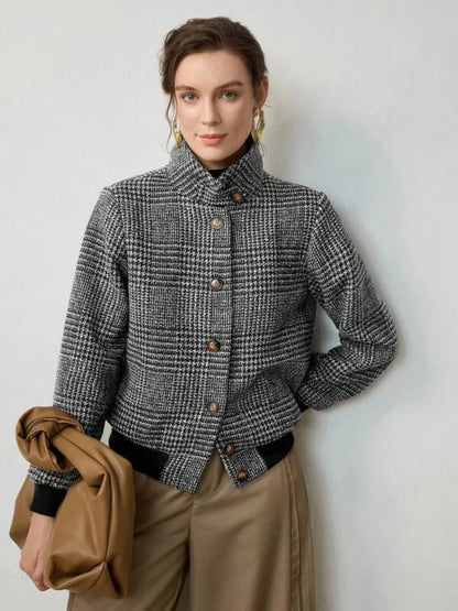 Woman wearing a checkered jacket holding a brown coat against a light background