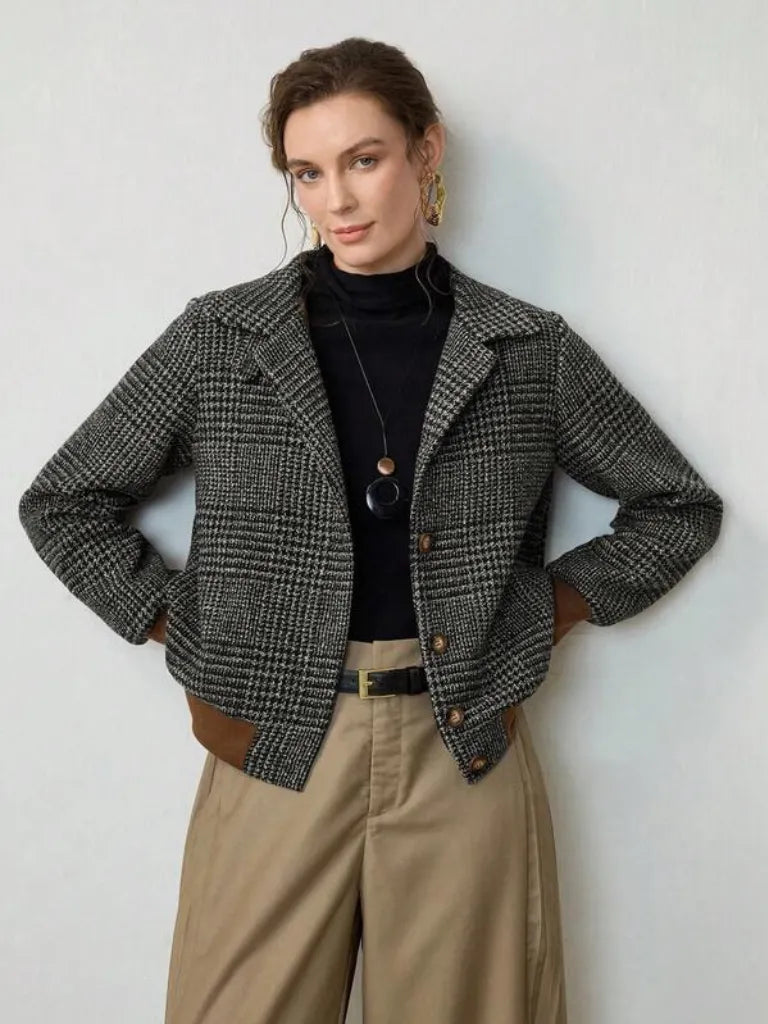 Woman wearing a plaid jacket, black turtleneck, and beige pants against a white background