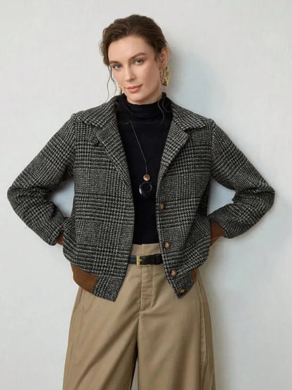 Woman wearing a plaid jacket, black turtleneck, and beige pants against a white background