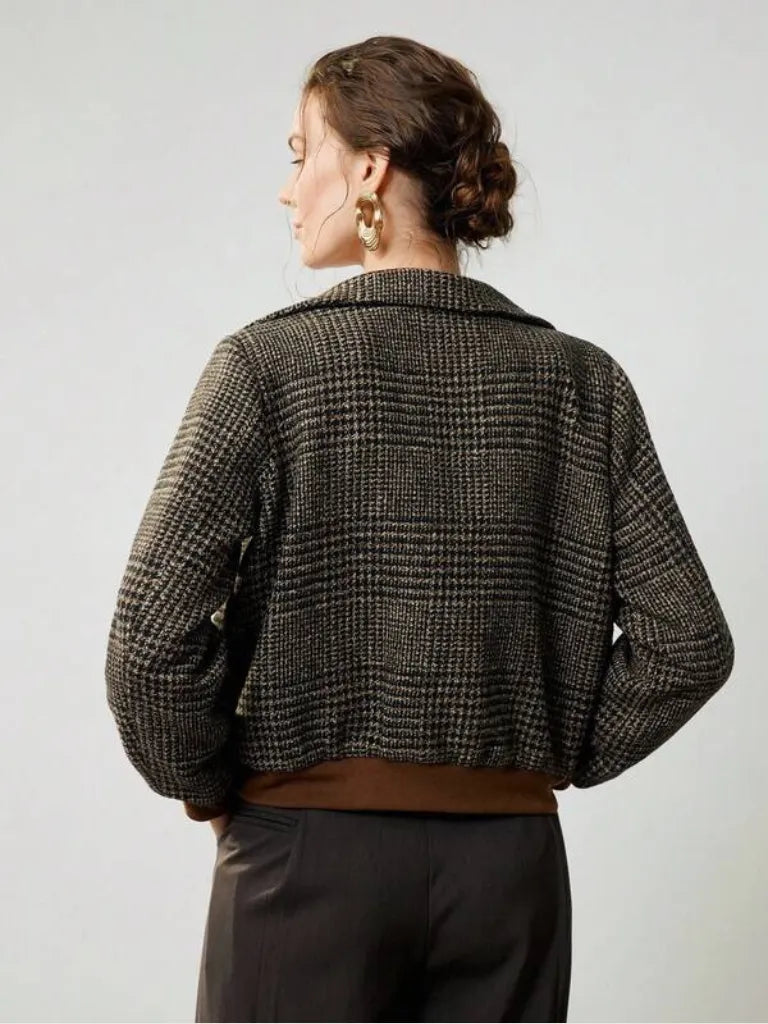 Person wearing a houndstooth patterned jacket on a plain background