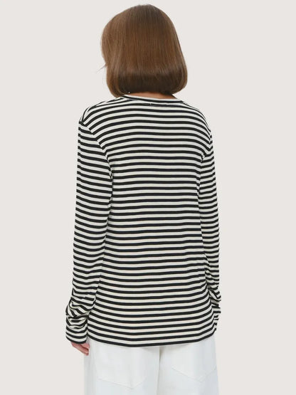 Person wearing a black and white striped long-sleeve shirt on a plain background