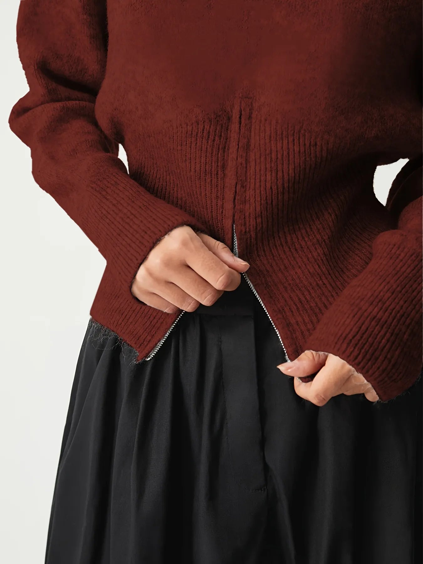 Person wearing a maroon sweater with a plain background