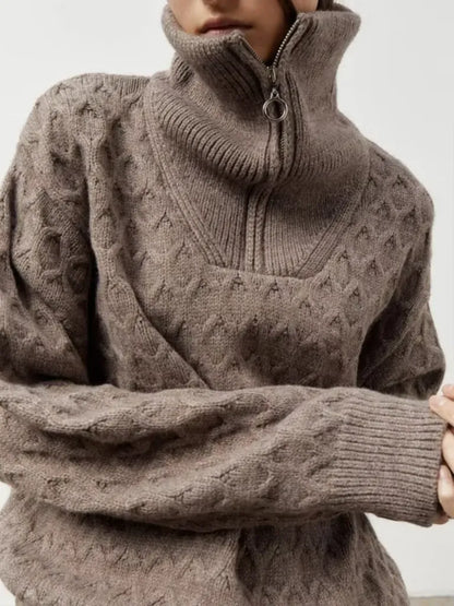 Close-up of a person wearing a brown cable knit sweater with a high collar.