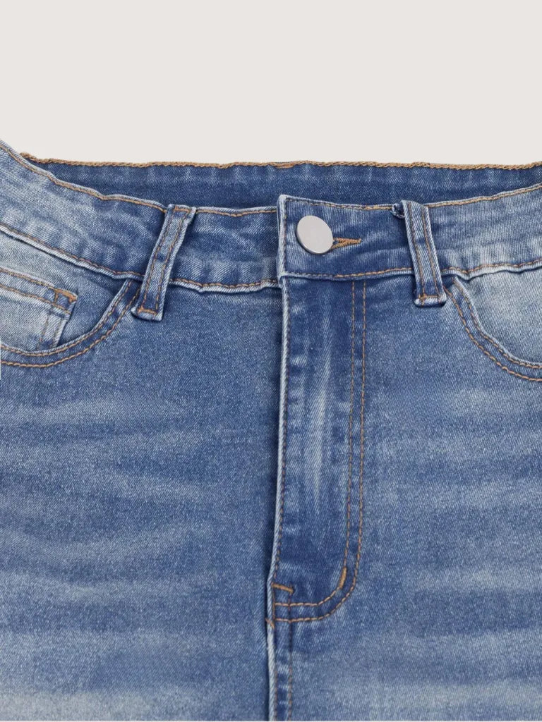 Close-up of blue denim jeans with a button and stitching details on a light gray background