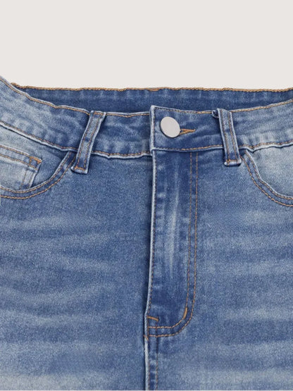 Close-up of blue denim jeans with a button and stitching details on a light gray background